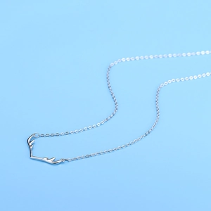Minimalist silver elk reindeer antler pendant necklace for women on a light blue background