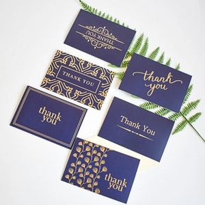 Detailed view of six dark blue thank you cards with premium gold foil stamped elegant designs