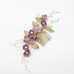 Close-up of golden bridal hair comb with purple fabric flowers and pearl accents