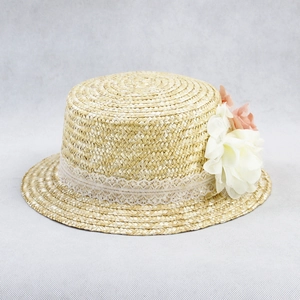 Detail of hand-woven straw hat featuring white lace trim and delicate chiffon floral decor