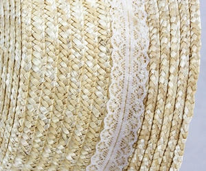 Close-up of wheat straw sun hat featuring intricate lace floral patterns and weaving