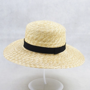 Classic flat top straw sun hat with wide brim and black ribbon on a minimalist stand