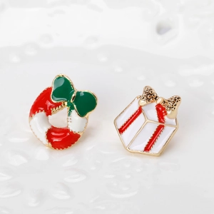 Close-up of enamel Christmas wreath and gift box brooch set with festive golden trim