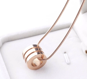 Macro shot of rose gold cylindrical triple ring pendant on sleek snake chain