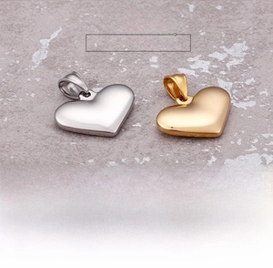 Polished silver and gold heart pendants with rings on a grey textured background