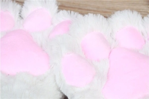 Close-up of white plush cat paw glove with soft pink pads and fluffy texture detail