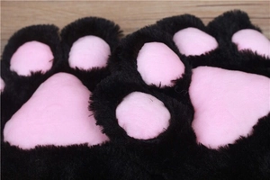 Close-up of black furry cat paw glove with pink soft pads on a wooden table