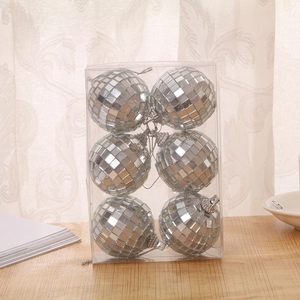 Close-up of six silver glass disco balls in a clear box on a bright wooden surface