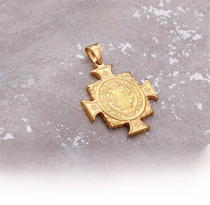 Macro detail of golden Saint Benedict cross pendant with embossed religious engravings