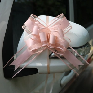 Dettaglio di un fiocco decorativo in organza rosa legato allo specchietto dell'auto