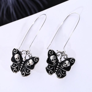 Close-up of gothic skull butterfly drop earrings with black enamel and silver finish