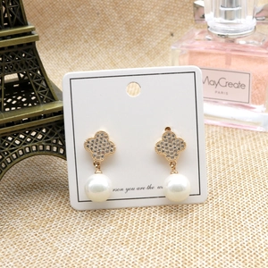 Golden clover earrings with zircon and pearls on display with Eiffel Tower decor