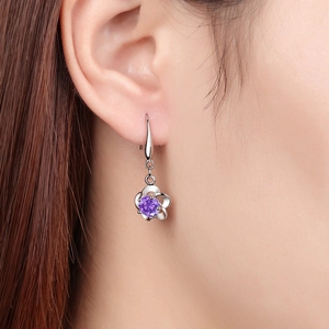 Silver flower earrings with purple crystals shown on model's ear for elegant look