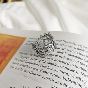 Macro detail of a 925 silver gothic cross ring placed on a vintage book page