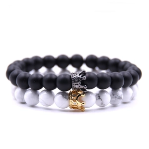 Détail de bracelets en pierre noire mate et blanche marbrée avec breloques couronnes serties