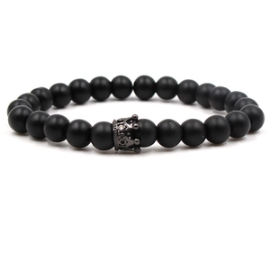 Détail d'un bracelet en perles noires mates avec un charm couronne en métal noir