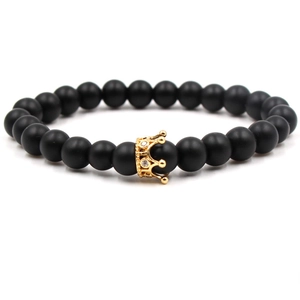 Détail de perles en pierre noire mate avec un pendentif couronne doré serti de zircons