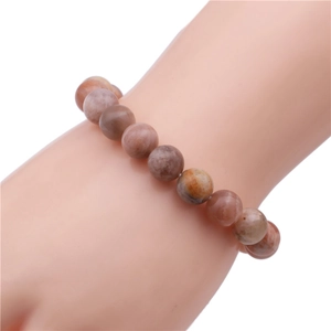 Close-up of 10mm natural agate beads on elastic bracelet with earthy brown and cream tones