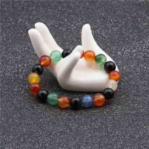 Detail of 10mm multi-color natural stone beads on a white hand-shaped jewelry display stand