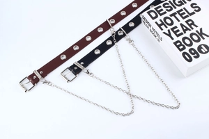 Detail eines Punk-Ledergürtels mit Ösen und einer dekorativen silbernen Metallkette
