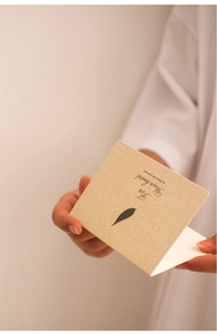 Close-up of a person opening a beige greeting card featuring a leaf pattern and quote