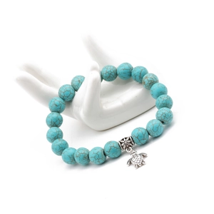 Detailed view of 10mm turquoise beaded bracelet with silver turtle and flower pendants