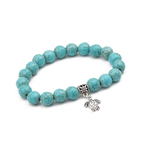 Detail of 10mm turquoise beaded bracelet featuring a silver sea turtle charm and carved bead