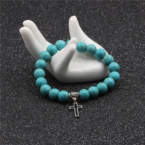 Detailed view of 10mm turquoise beaded bracelet featuring a silver metal cross pendant