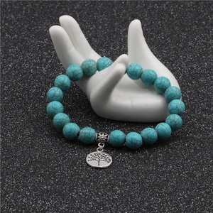 Detail of 10mm turquoise bead bracelet with silver tree of life charm on ceramic hand