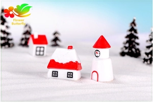 Detailed close-up of miniature snowy resin house and clock tower christmas decorations