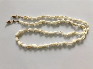 Detail view of natural white seashell eyeglass chain with golden lobster clasps