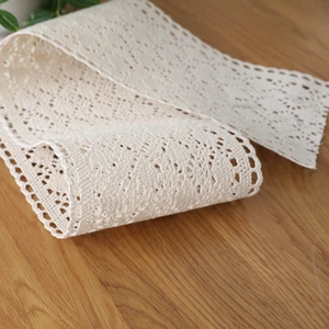 Beige handmade crochet cotton lace runner displayed on a rustic wooden table surface