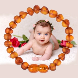 Natural Baltic amber baby teething bracelet with orange beads on white plush rug background