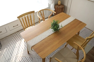 Close-up of beige crochet table runner with hollow lace patterns on wooden surface