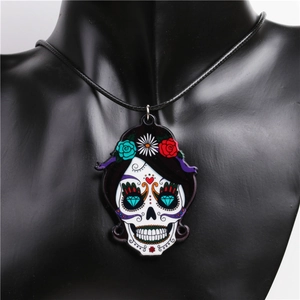 Close-up of a colorful skull pendant with floral patterns on a black woven cord necklace