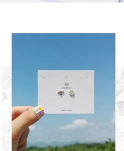 Detailed view of asymmetric bee and daisy flower studs against a natural landscape
