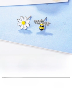 Macro view of asymmetrical flower and bee stud earrings set in 925 sterling silver