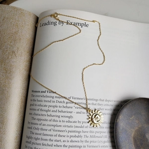 Detailed shot of a gold sun and moon pendant necklace resting on a vintage book page