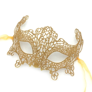 Detailed close-up of golden lace masquerade mask with intricate cutout patterns and ribbons