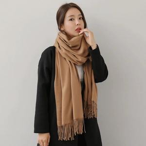 Elegant camel brushed cashmere scarf with tassels styled on a black coat for winter warmth