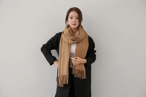 Detailed close-up of a camel cashmere scarf with elegant fringe tassels for women