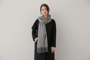 Detail of light gray cashmere scarf featuring soft texture and classic fringe tassels