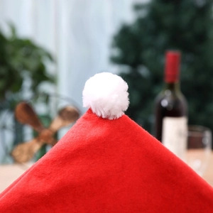 Gros plan d'une housse de chaise de Noël rouge ornée d'un pompon blanc moelleux en haut