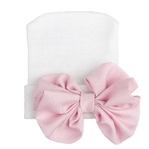 Close-up of white knitted baby hat featuring a large soft pink chiffon bow detail