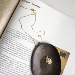Vintage 925 sterling silver gold moon sun pendant necklace on an artistic book background