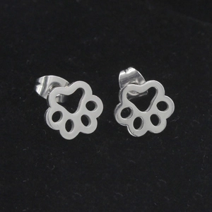 Polished silver stainless steel dog paw stud earrings on black velvet background