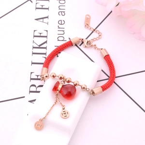 Vista macro del bracciale in corda rossa con ciondoli a forma di zucca oro rosa
