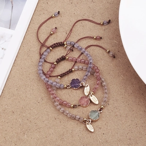 Detail of three handmade braided stone bracelets with pink and purple natural pendants