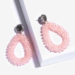 Detail van handgemaakte roze kralen oorbellen in druppelvorm met kristallen knopjes