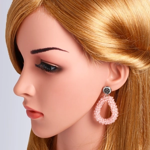 Detail van roze kralen oorbellen in druppelvorm met zwarte strasstenen op model
